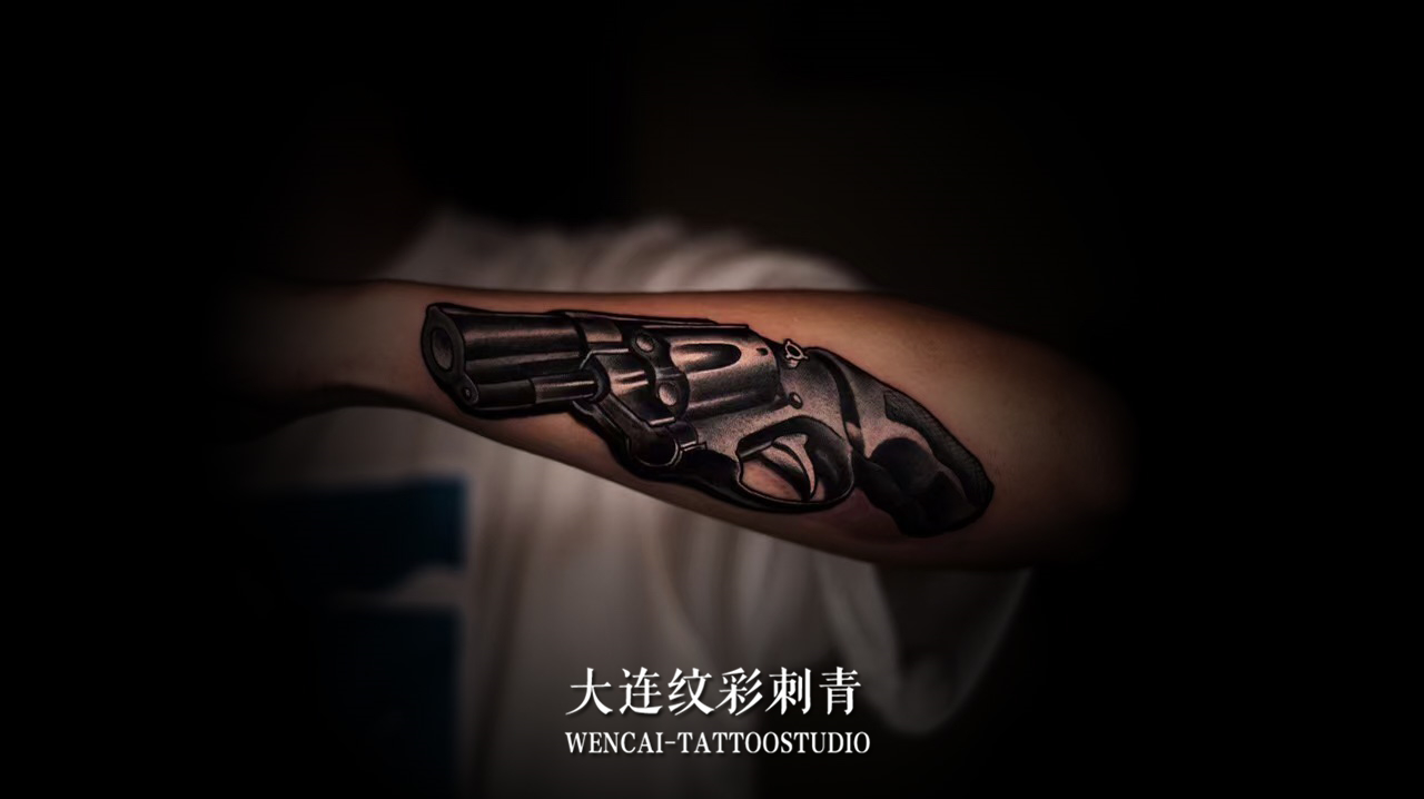 健身教练孙先生手臂处的酷炫手枪纹身图案