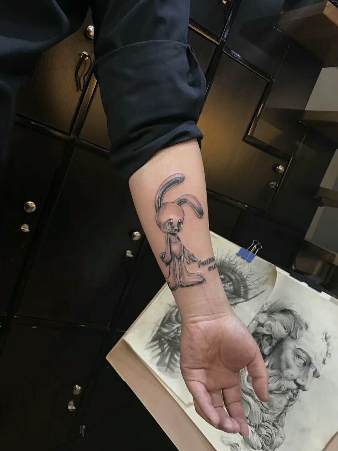 小臂充满爱的黑灰兔子玩偶纹身图案